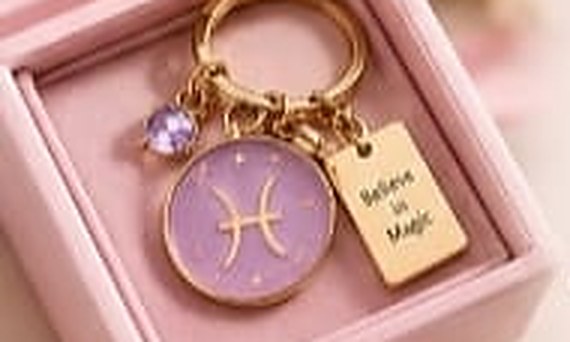 A zodiac keychain in an open blush gift box